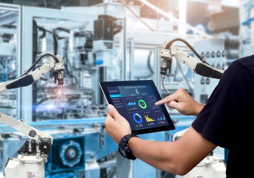 Smart industry control concept.Hands holding tablet on blurred automation machine as background