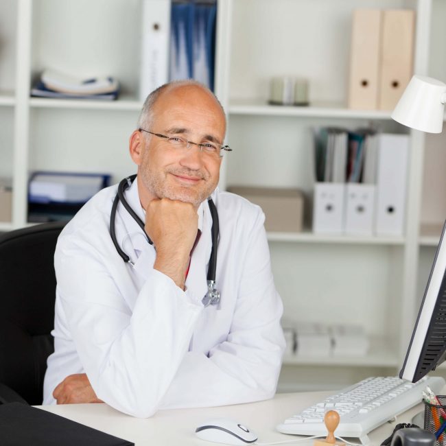 lächelnder arzt am schreibtisch